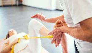 physiotherapist doing exercises with a band on patients foot and leg